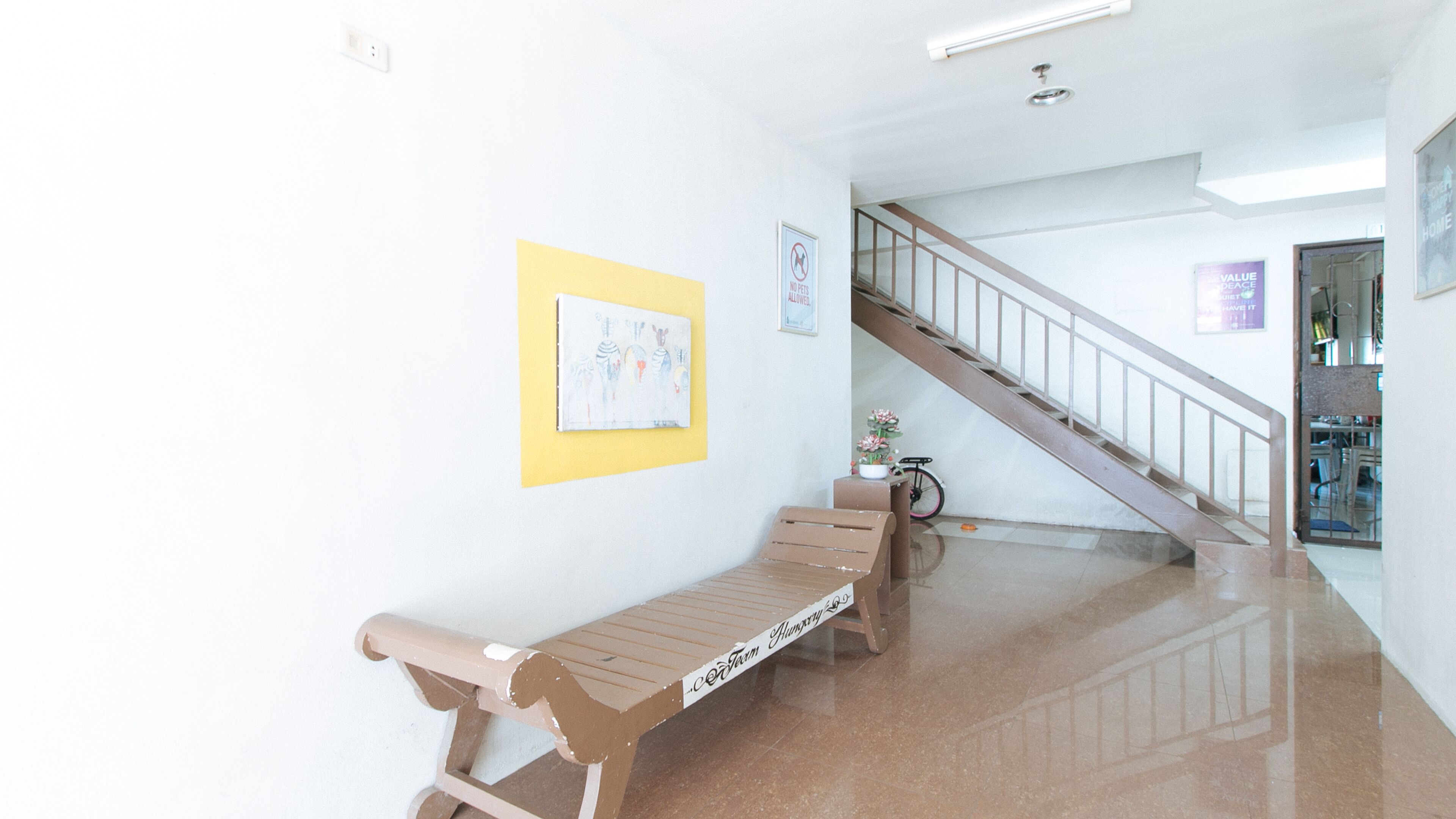 A hallway with a wooden bench, a bicycle, and a staircase.