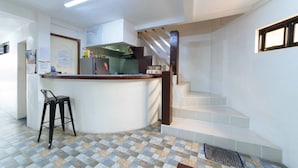 Une cuisine avec un comptoir-bar, un tabouret et un escalier.
