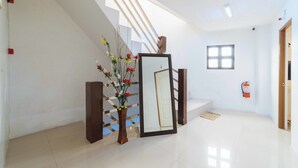 Un intérieur moderne agrémenté d’un escalier, d’un grand miroir et d’un vase rempli de fleurs.