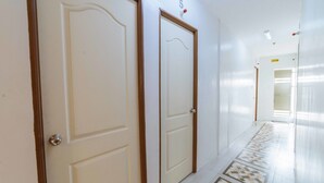 Un couloir avec deux portes, dont l’une est marquée du numéro 5, et un sol à motifs.