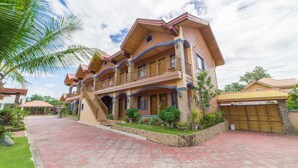 A multi-story house with a balcony, a stone foundation, and a tiled driveway. - RedDoorz Plus @ Starhomes Olivianville (Tarlac)