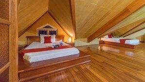 An attic bedroom with a large bed, a smaller bed, wooden flooring, and a sloped ceiling. - RedDoorz Plus @ Starhomes Olivianville (Tarlac)