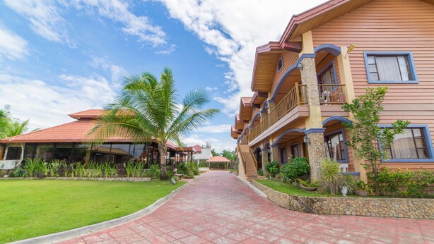 A pathway leading to a building with multiple balconies and a red-tiled roof. - RedDoorz Plus @ Starhomes Olivianville (Tarlac)