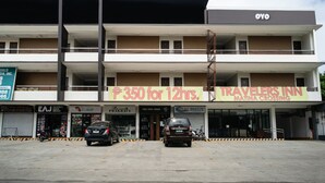 Un edificio de varios pisos con un letrero que indica Travelers Inn y un precio de ₱350 por 12 horas.