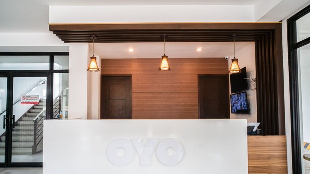Una recepción con el logotipo “OYO” y tres lámparas colgantes.
