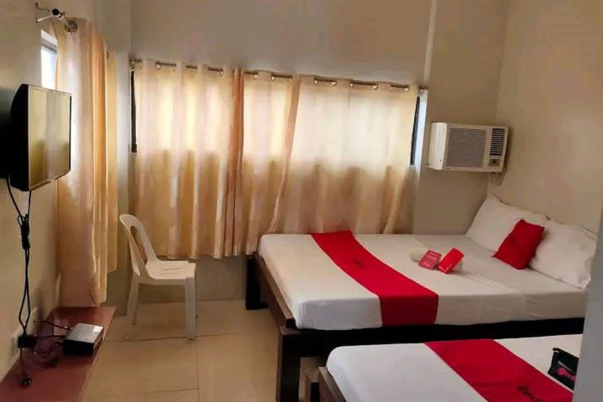 Quarto de hotel com duas camas, uma escrivaninha, uma cadeira, uma televisão e um aparelho de ar condicionado.