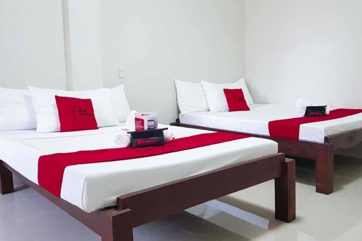 Two single beds with white bedding and red accents, wooden headboards, and a red throw blanket on each bed.