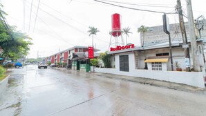 A street with a RedDoorz building, a water tower, and palm trees. - RedDoorz Premium @ Clarkview Angeles City (Angeles City)