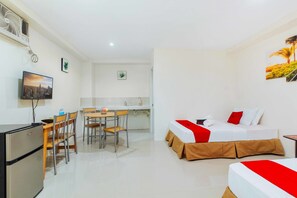 Una habitación de hotel compacta con cama, escritorio y kitchenette.