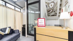 A modern hotel reception area with a sofa, a desk, a lamp, and a sign for RedDoorz. - RedDoorz @ Salinas Extension Lahug (Cebu City)