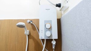 A bathroom with a white Panasonic water heater, a showerhead, and a control panel with a main switch and power control. - RedDoorz @ Vicente Street Espana Manila (Manila)