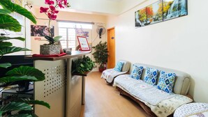 A cozy room with a sofa, a small table with a potted plant, a wall clock, and a framed picture. - RedDoorz @ Vicente Street Espana Manila (Manila)