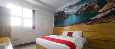 A hotel room with a bed, a wooden headboard, a large window, and a mural of a coastal landscape.