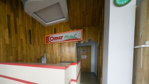 Un comptoir d’accueil avec une enseigne indiquant « Hôtel Omar ».