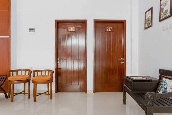 A reception area with two wooden doors labeled 216 and 217, a bench with a framed picture, and two wooden chairs with orange cushions.