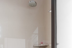 A bathroom with a shower, a mirror, and a shelf with a bottle.