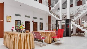 A spacious lobby with a high ceiling, a staircase, and a reception desk. - RedDoorz near Jawa Timur Park 3 (Batu)