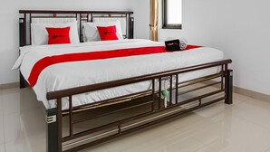 A neatly made bed with a wooden frame, white bedding, and red accents. - RedDoorz near Jawa Timur Park 3 (Batu)