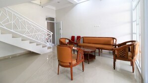 Un salon moderne avec un ensemble de canapés en bois, une table basse et un escalier doté d’une rampe aux motifs géométriques.