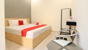 Une chambre d’hôtel moderne avec un lit en bois, un plaid rouge, une table de chevet et un téléviseur fixé au mur.