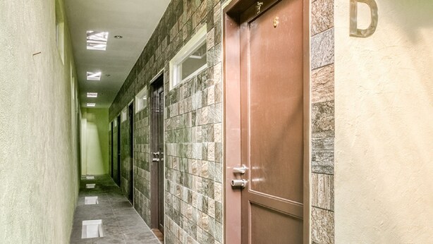 A hallway with tiled walls and a brown door. - RedDoorz @ Panglima Polim 2 (Jakarta)