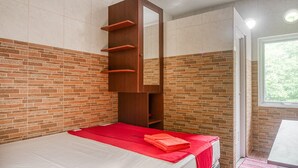 A room with a bed, a wooden shelf unit, and a window. - RedDoorz @ Panglima Polim 2 (Jakarta)