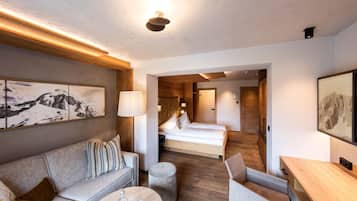 Ett modernt hotellrum med ett träpanelat tak, en säng, en soffa, ett skrivbord och en tavla på väggen.
