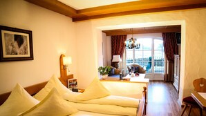 Une chambre d’hôtel avec un lit, un bureau, une chaise, une lampe, une plante et une vue sur l’extérieur.