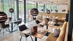 A modern dining area with tables, chairs, and hanging spherical light fixtures. - Rossalpe - Hotel Bogner Hof (Bogen)