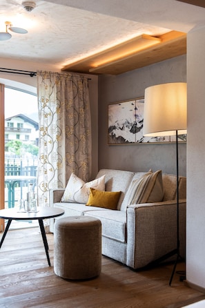 Un salon avec un canapé, un pouf, une lampe sur pied et un tableau accroché au mur.