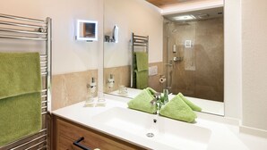 A modern bathroom with a wooden ceiling, a large mirror, a sink, and a shower.