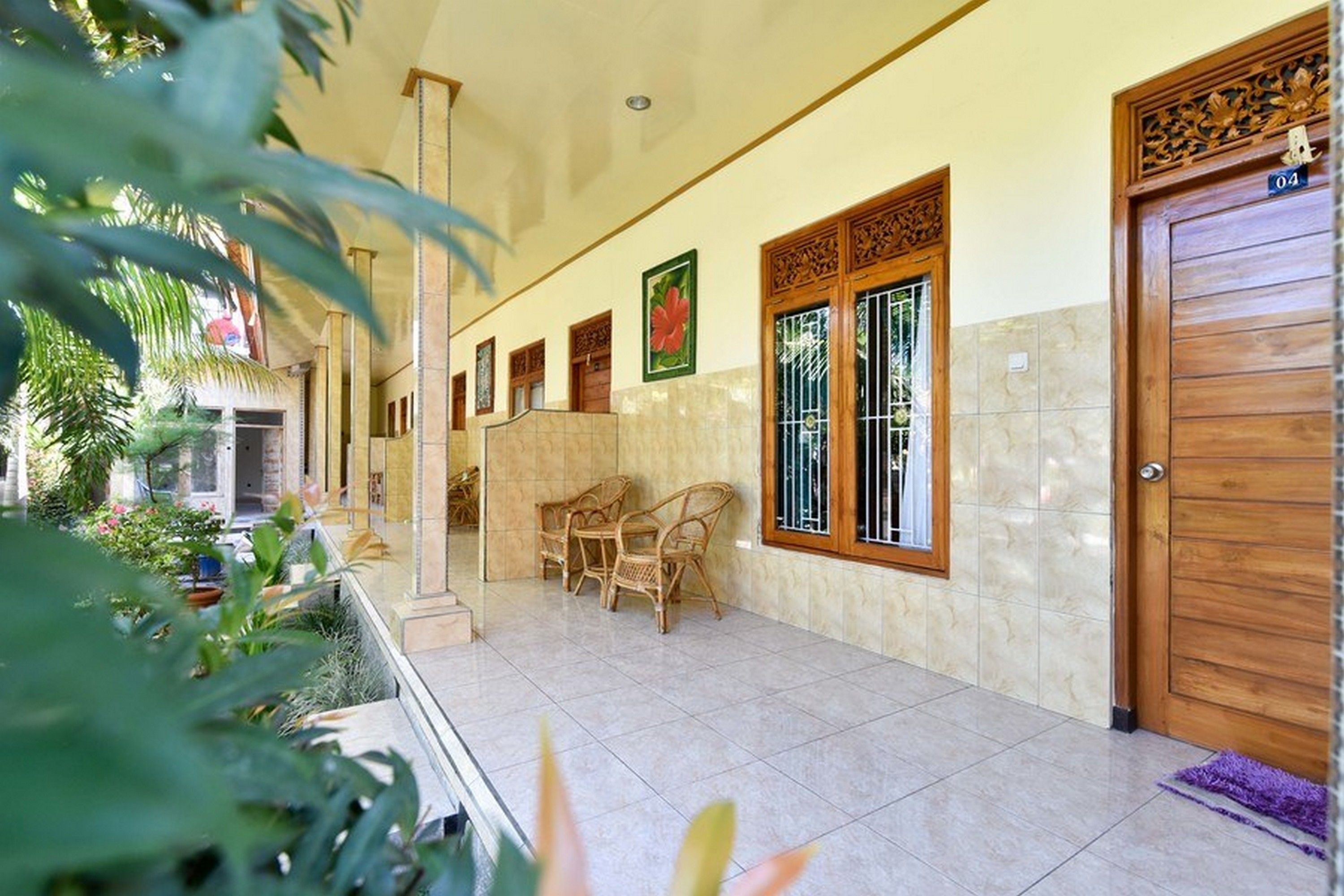 A hotel corridor with tiled flooring, wooden doors, and wicker chairs.