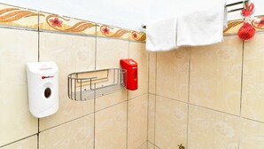 Une salle de bain équipée d’un distributeur de savon liquide, d’un distributeur d’essuie-tout et d’un porte-serviettes sur lequel est posée une serviette blanche.