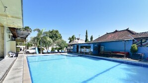 Une piscine avec des chaises longues et un bâtiment doté d’un toit en tuiles.