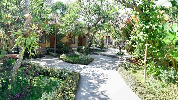 Un chemin de jardin qui mène à un bâtiment à la façade jaune et au toit rouge.