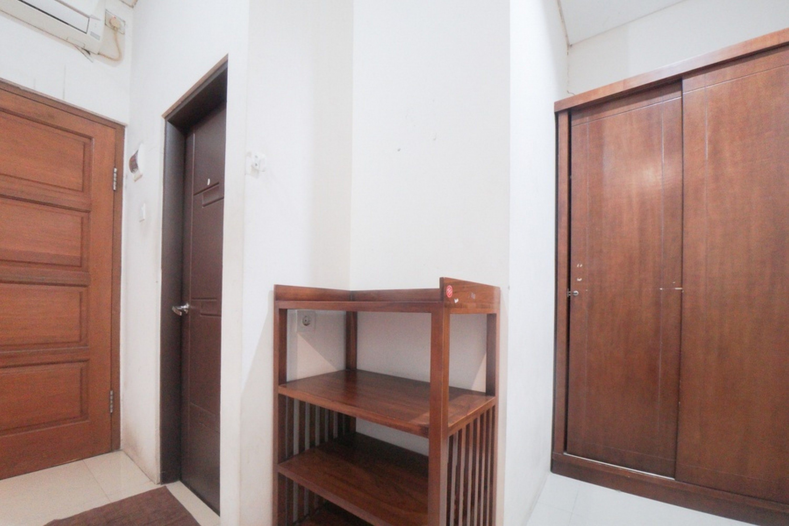 A room with a wooden door, a wooden shelf unit, and a wooden wardrobe.