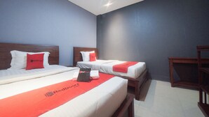 Habitación de hotel con dos camas, cada una con ropa blanca y detalles rojos, y cabeceros de madera.