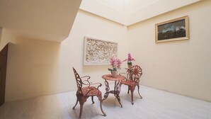 Una habitación con techo alto, tragaluz, dos sillas, una mesita y una planta en maceta.