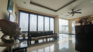 Un salón amplio con un gran ventanal, un ventilador de techo y un sofá.