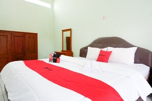 A neatly made bed with a red and white bedspread, a wooden wardrobe, and a mirror on the wall.