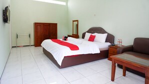 A bedroom with a bed, a nightstand, a sofa, a wooden wardrobe, a mirror, and a radiator.