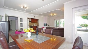 Una sala de estar moderna con una mesa de comedor de madera, un sofá y una cocina al fondo.