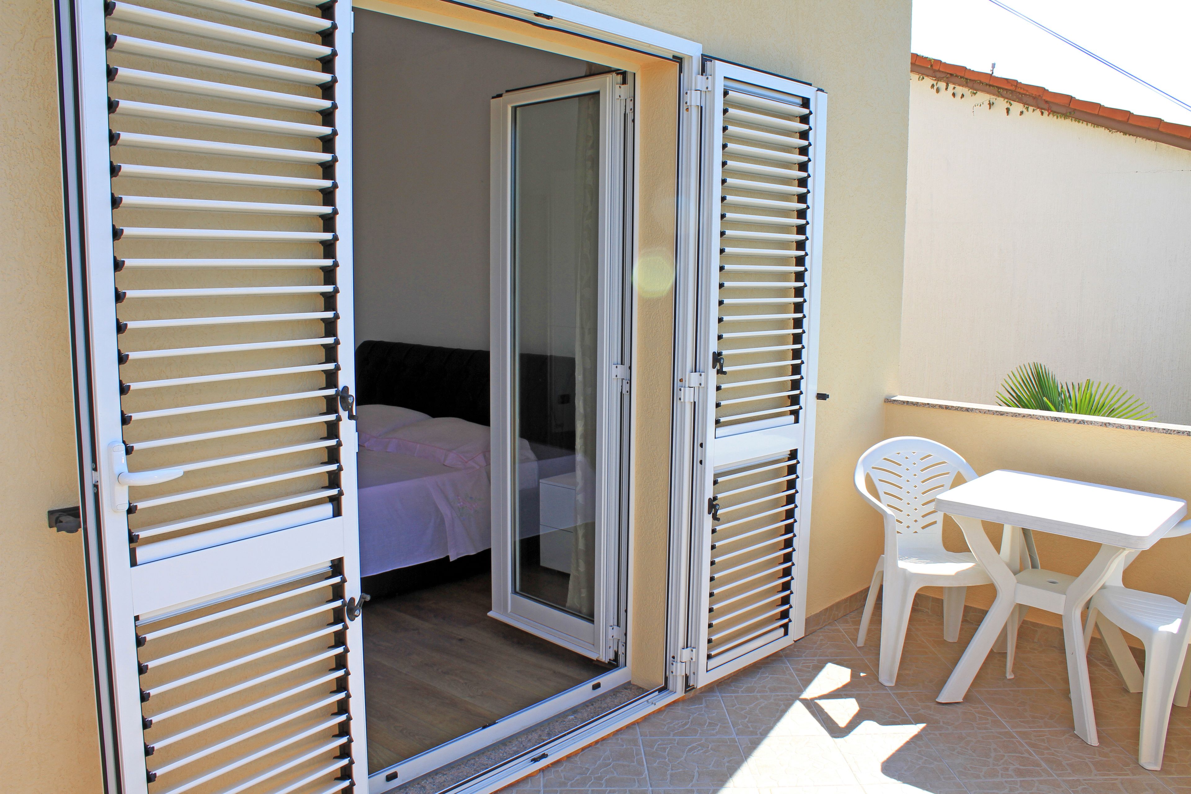 A room with a bed, a sliding glass door, and a small patio area with a table and chairs.