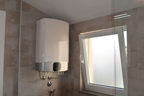 Klassiek appartement | Badkamer | Een douche, een haardroger, handdoeken, zeep