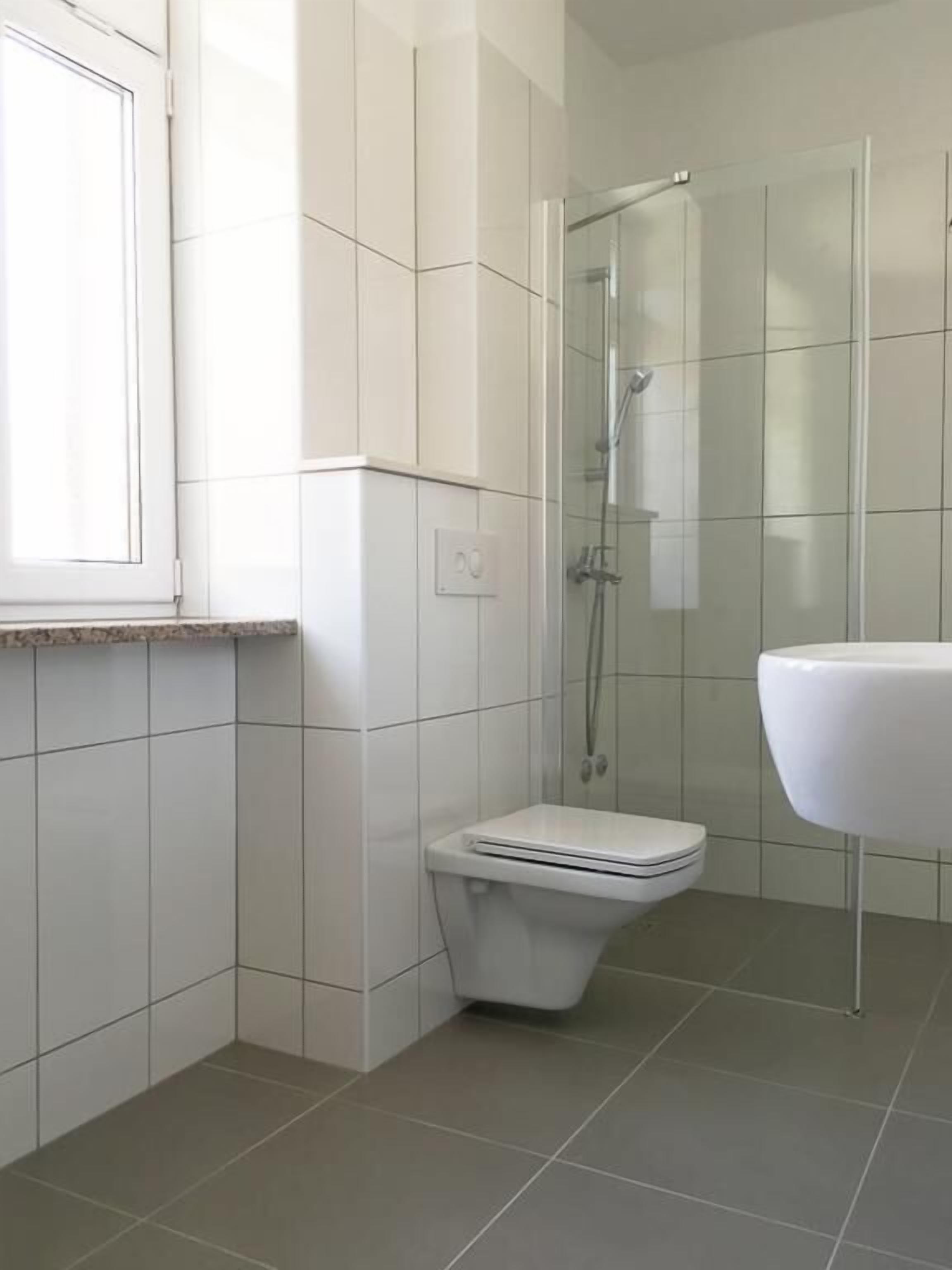 A modern bathroom with a toilet, shower, and sink.