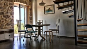 Un comedor con mesa y sillas, una escalera y una pared de piedra.