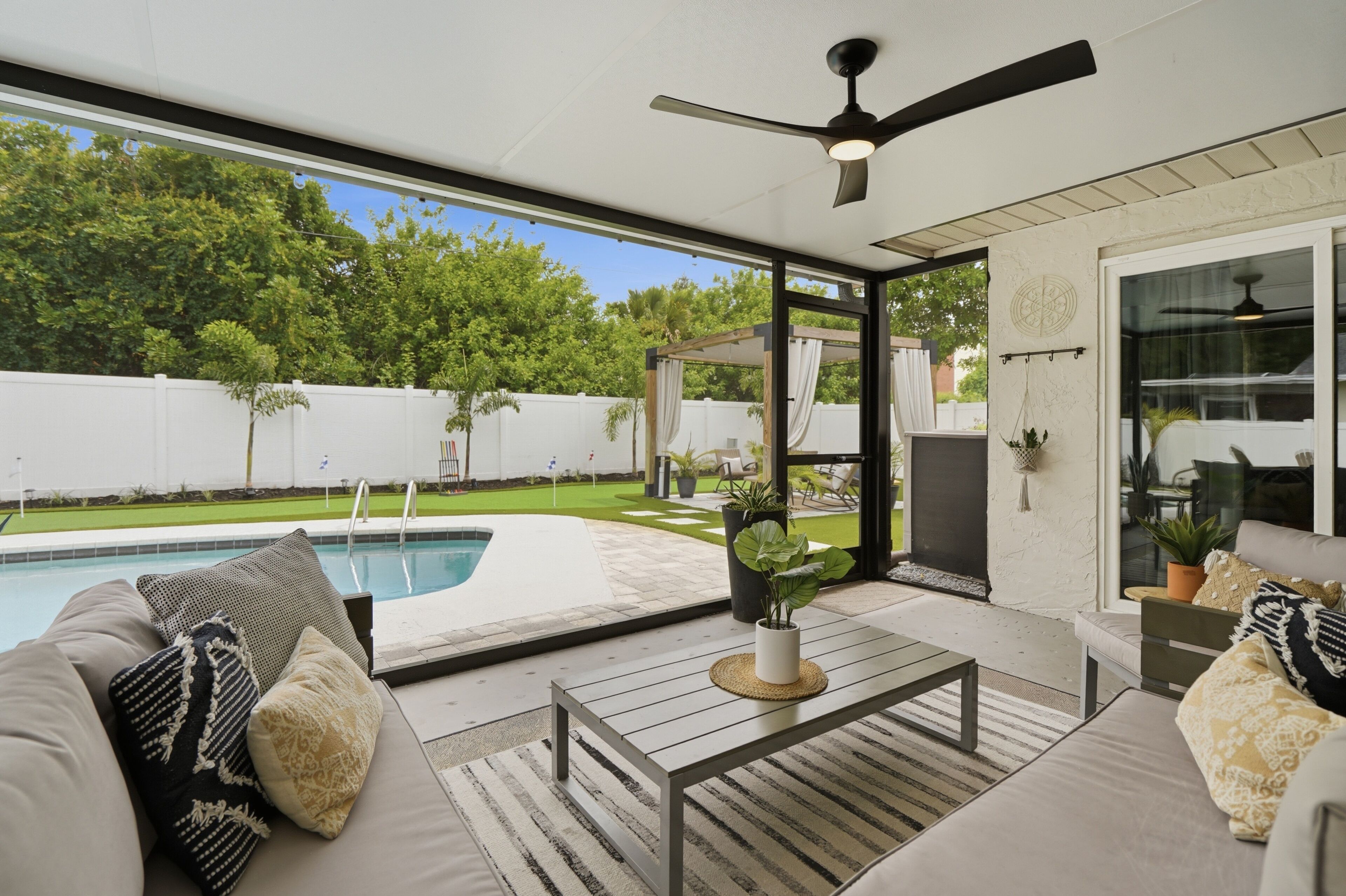 Eine Außenpatio mit Pool, Sitzgelegenheit und Deckenventilator.