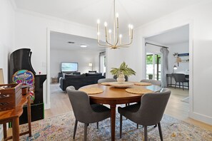 Ein Essbereich mit einem runden Holztisch, grau gepolsterten Stühlen und einer hängenden Chandelier.