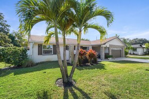 A single-story house with a garage, a well-maintained lawn, and a palm tree in the front yard.