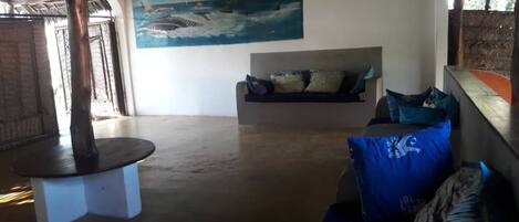 Ein Zimmer mit einem runden Tisch, einer Couch mit Kissen und einem Gemälde eines Schiffes an der Wand.